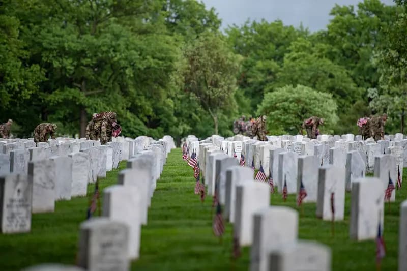 Rows of white headstones with small American flags at Arlington National Cemetery during Flags-In